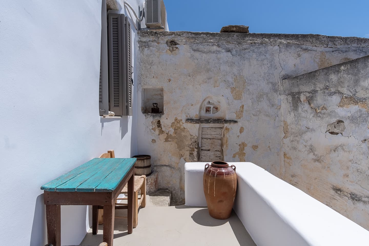 The upstairs terrace kitchenette corner at Casa di Lavalle, with a weathered stone wall and a painted teal table.