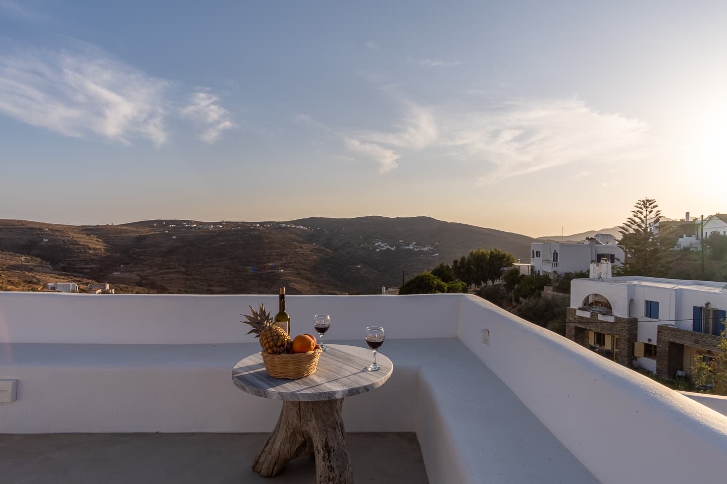 Sunset over the Tinos hillside seen from the terrace at Casa di Lavalle, with wine and fruit set on the table.